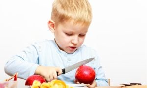 boy with sharp knife cutting apples