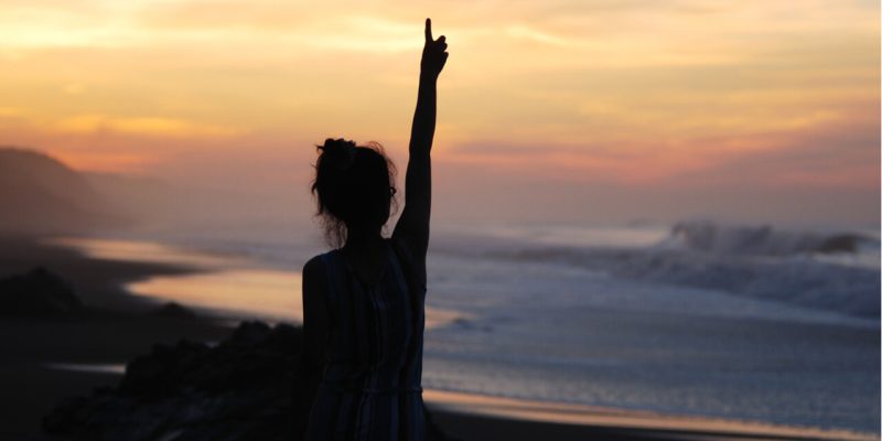 woman in silhouette with arm in air
