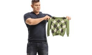 man holding up shrunken sweater