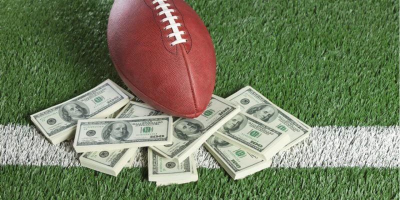 Football on a field with some dollar notes