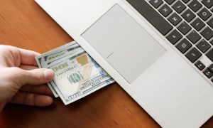 Hundred dollar bills coming out of a laptop