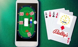 phone displaying online casino app on green felt next to playing cards bearing bally's logo and rhode island seal