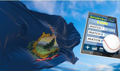 vermont flag flies against a blue sky next to a tablet operating an online sportsbook