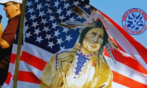 Seneca Native American speaks During Rally With American Flag and Seneca Nation logo