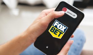 person powering down cell phone with foxbet logo on the screen