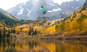 colorado mountains, lake, and forest surrounding sporttrade logo