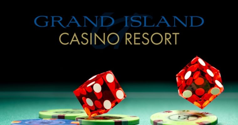 dice falling onto gaming chips on felt table under grand island casino logo