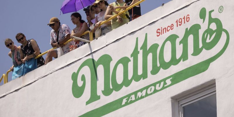 people standing above nathan's famous hot dog stand on coney island
