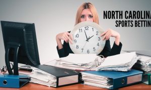 Woman Holds Clock At Cluttered Work Desk with North Carolina sports betting