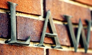 Word Law In Metal Hangs On Brick Wall