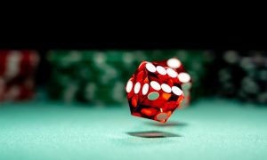 Single Red Dice Rolls On Casino Game Table
