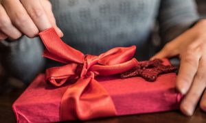 hands pulling bow on gift box