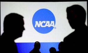 People Talk In Front Of NCAA Logo