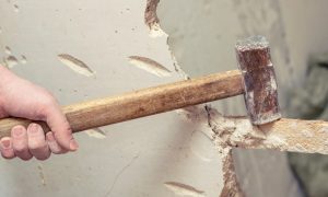 hand smashing wall with hammer