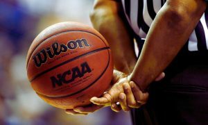Official Holds NCAA Basketball At Game