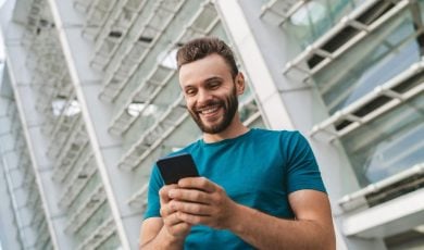 Happy Man Looks At Cell Phone