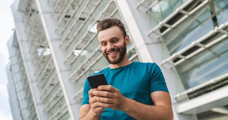 Happy Man Looks At Cell Phone