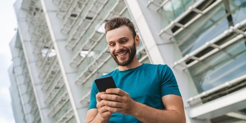 Happy Man Looks At Cell Phone