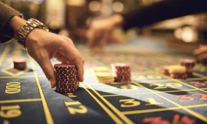 Man Places Stacked Red Chips On Roulette Table