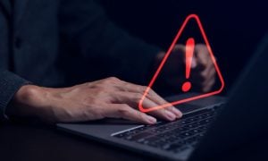Man On Laptop With Red Warning Sign