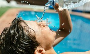 Boy Splashes Face With Water On Hot August Day