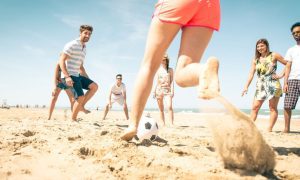 Young Friends Playing Soccer On The Beach