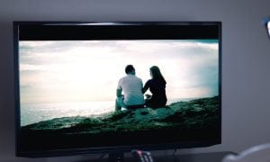 person holding remote watching television