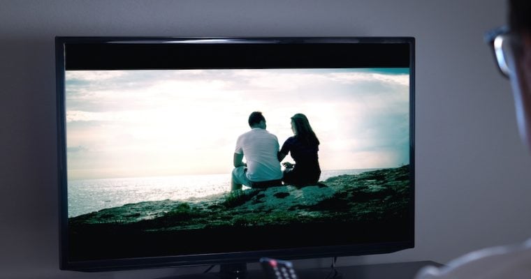 person holding remote watching television