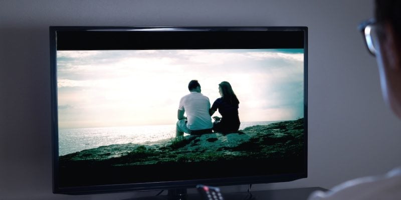 person holding remote watching television