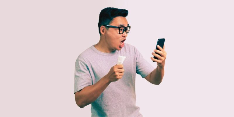 Asian Man With Thick Black Glasses Holds Lottery Tickets, Phone