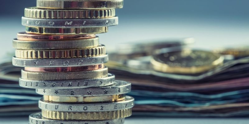 Stacked Coins In Forefront Money Laying In Background