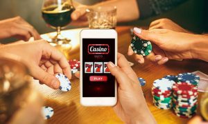 a group of people playing poker while one holds a phone with a casino game on it