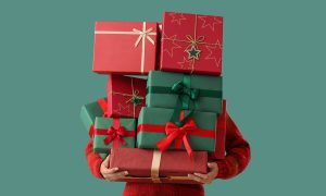 person with arms full of christmas gifts on a green background