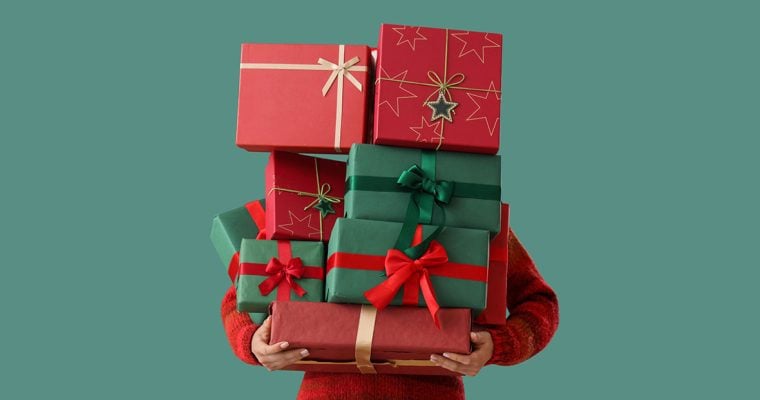 person with arms full of christmas gifts on a green background