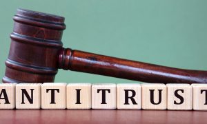 a court gavel sitting behind tiles that spell antitrust
