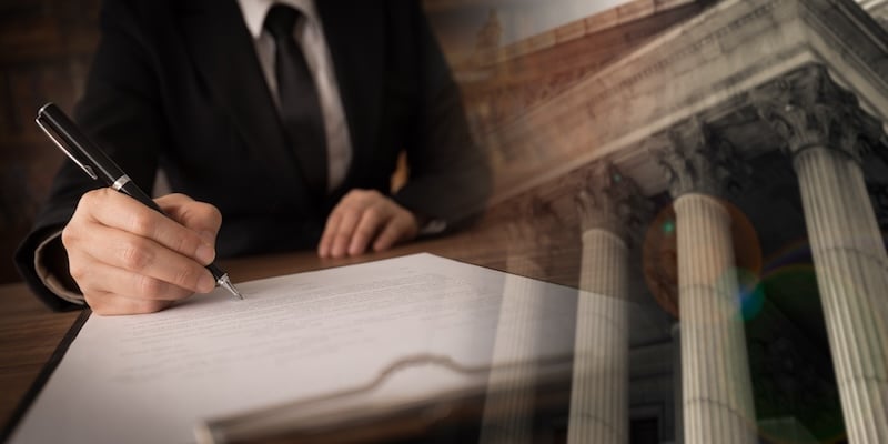 hand signing papers besides building columns