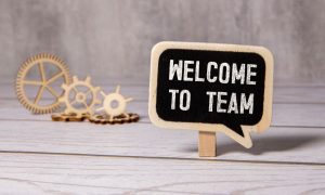 a sign of welcome to the team next to a pair of gears