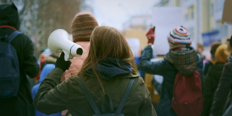 a collection of people on strike with one holding a megaphone