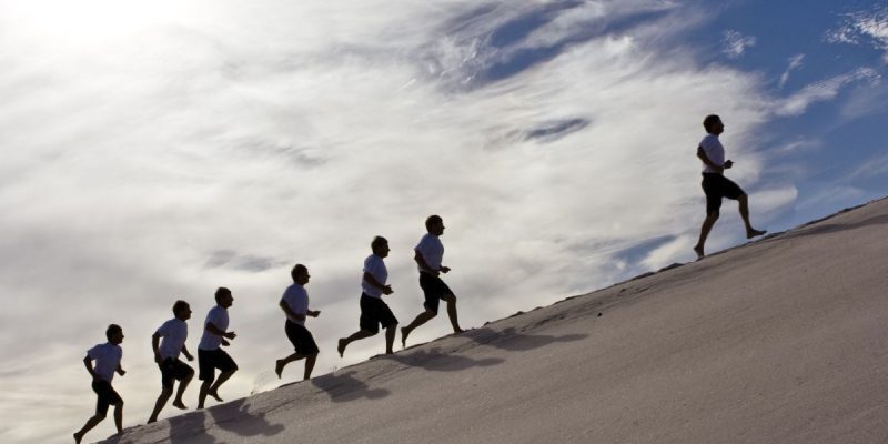 a series of men racing up a sandy hill