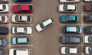 a car struggling to park in a crowded parking lot