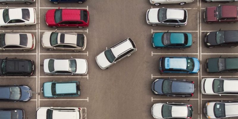 a car struggling to park in a crowded parking lot