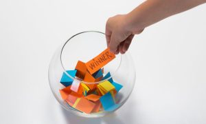 a fish bowl with tickets, where a hand draws out a winner