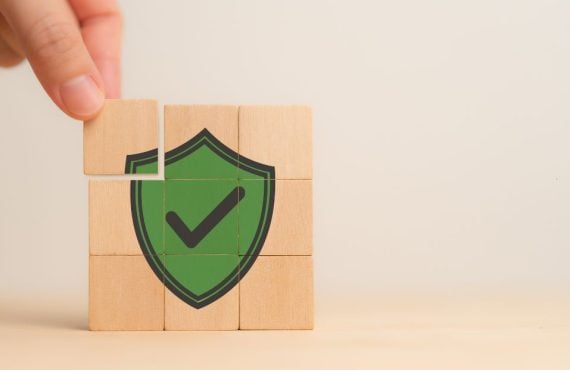 a hand building blocks that make out a green check mark security shield