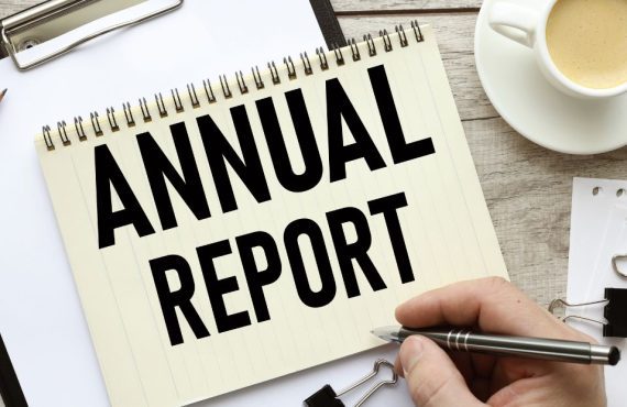a table filled with work supplies and a notebook that says annual report on it