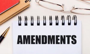 a notepard with amendment on it surrounded by office supplies and glasses