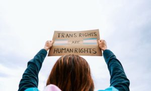 a woman holding up a sign that says trans rights are human rights