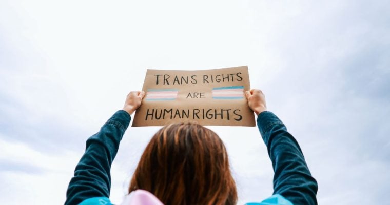 a woman holding up a sign that says trans rights are human rights