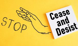 a drawn hand between the word stop and a cease and desist sign
