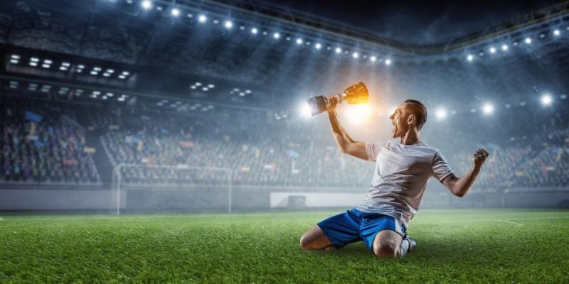 a soccer player celebrating with a trophy