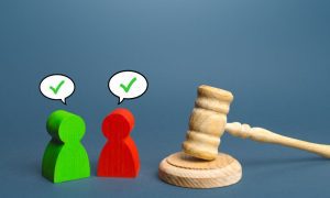 a pair of wooden people coming to agreement next to a wooden gavel